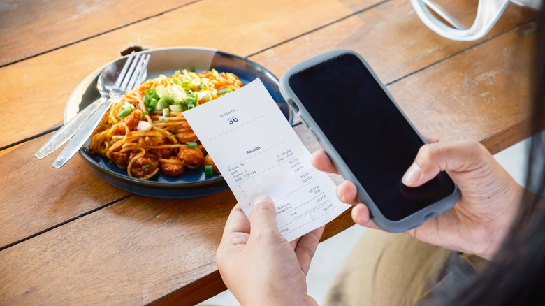 Person holding food receipt over meal