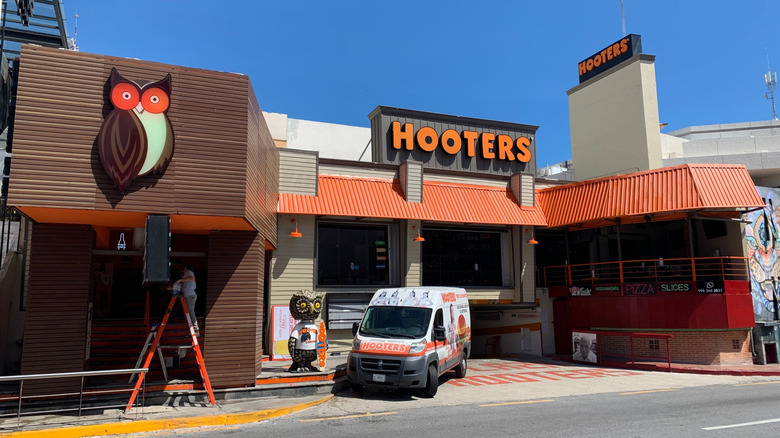 A Hooters location on a bright blue day, featuring two iterations of the company's owl logo.