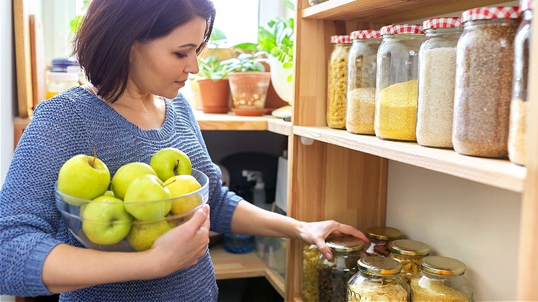 Person holding apples, reviewing pantry