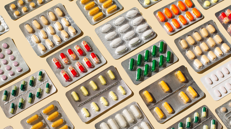 An array of pills in blister packs against a beige background