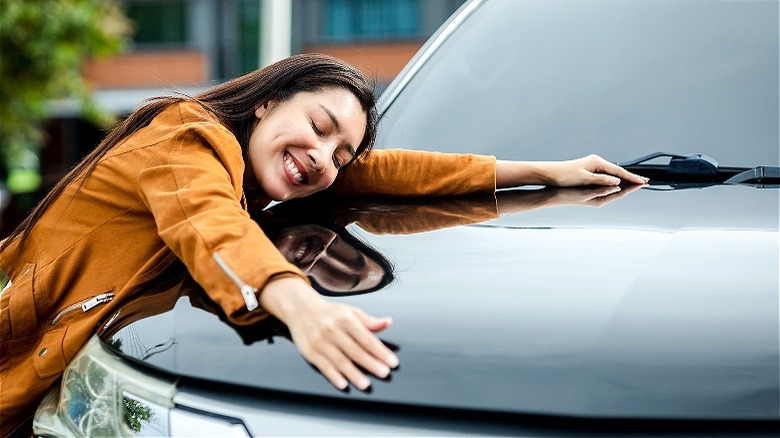 Person smiling while hugging car