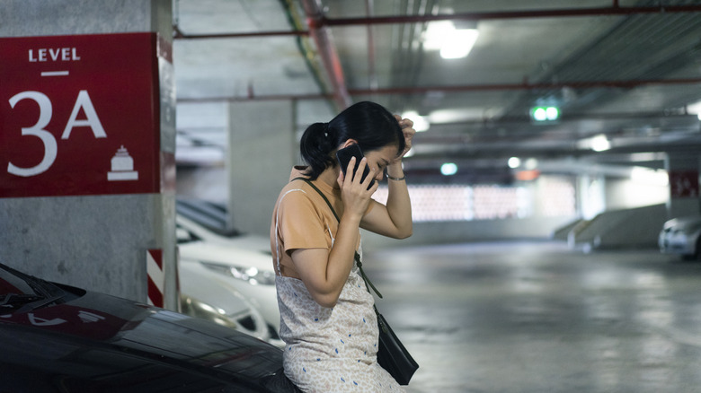 A woman in a parking lot making a phone call