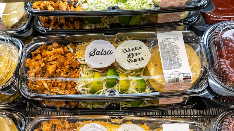 A Costco chicken salad kit, amidst a chilled stack of same.