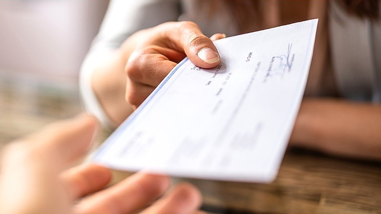 Person handing paper paycheck to someone