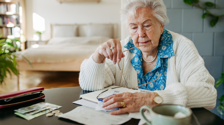 A senior sitting at table looking over financial documents