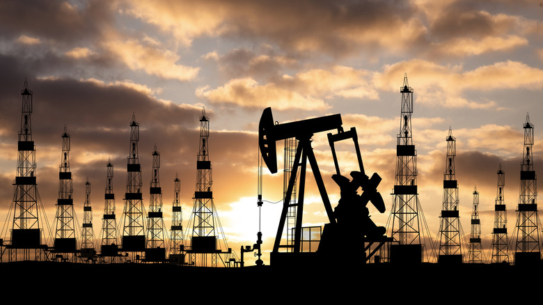 Silhouetted equipment on an oil field at dusk