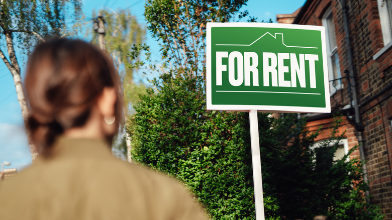 woman looking at for rent sign