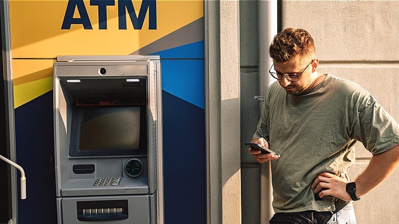 Person reading phone near ATM