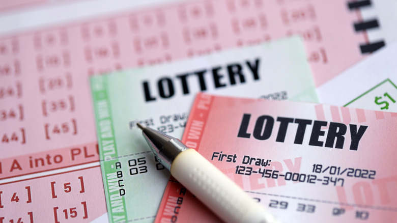 A pen sitting on top of lottery tickets.