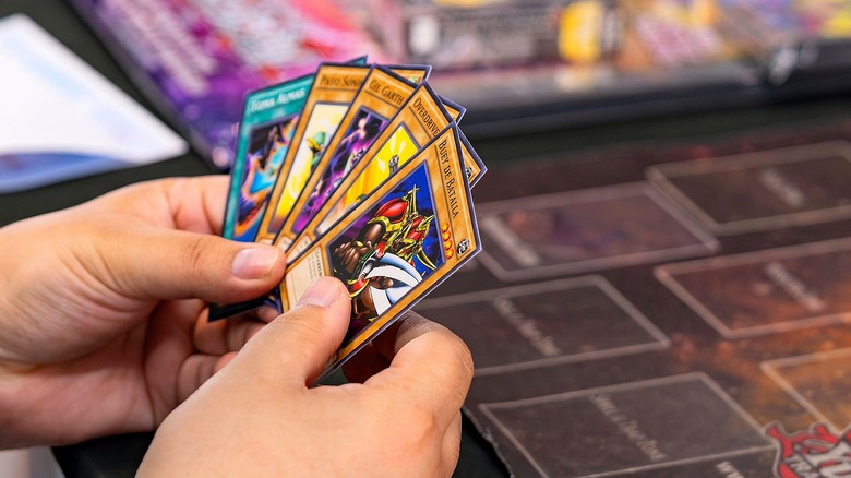 Person holds Yu-Gi-Oh! cards in hands during game