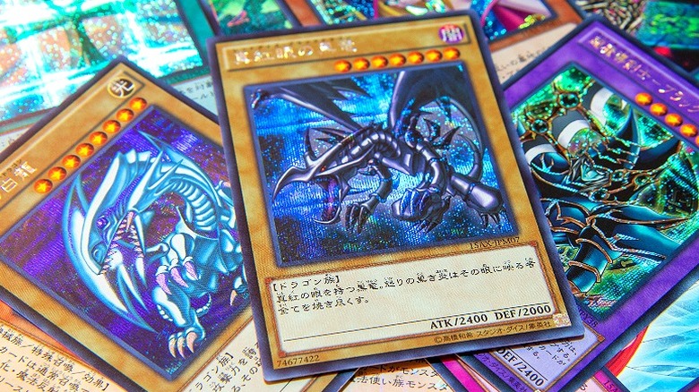 Three Yu-Gi-Oh! cards including Blue Eyes White Dragon (left card)