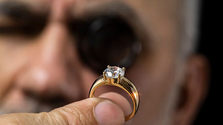 A man closely inspecting a ring.