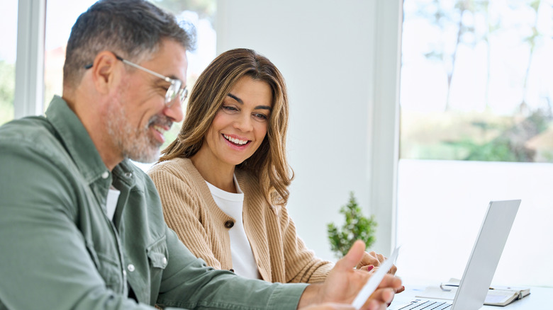 Mature couple using laptop counting taxes refund receipts