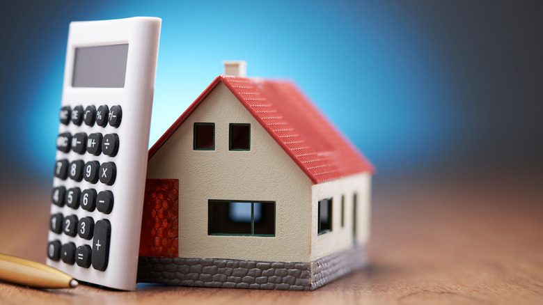 Calculator and pencil lean against model house