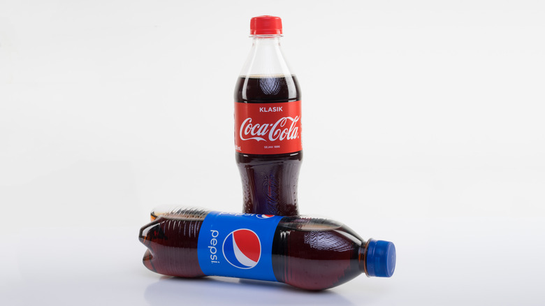 Coca-Cola bottle standing next to an overturned Pepsi bottle