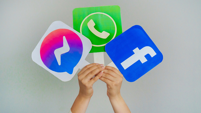 Teen hands hold Facebook, What's App, and Messenger logos