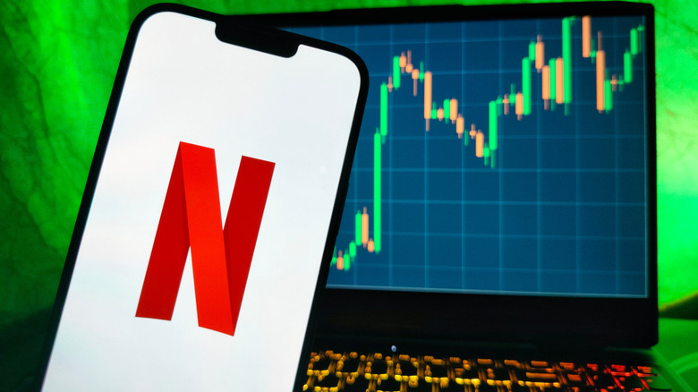 Netflix logo on smartphone overlaying NFLX stock chart