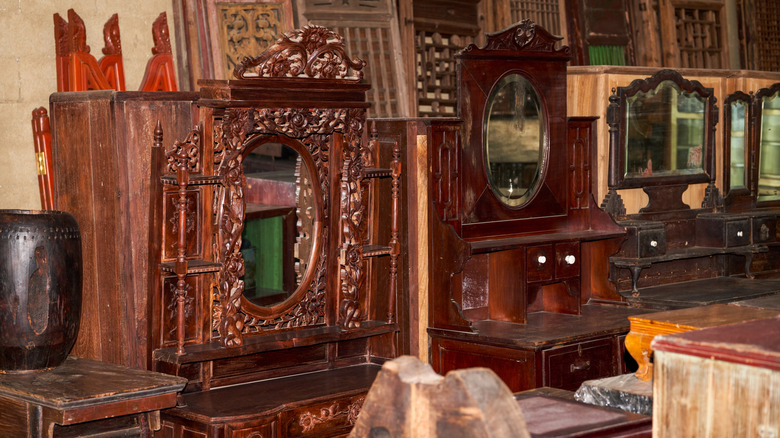 A crowded antique furniture section full of brown vanities.