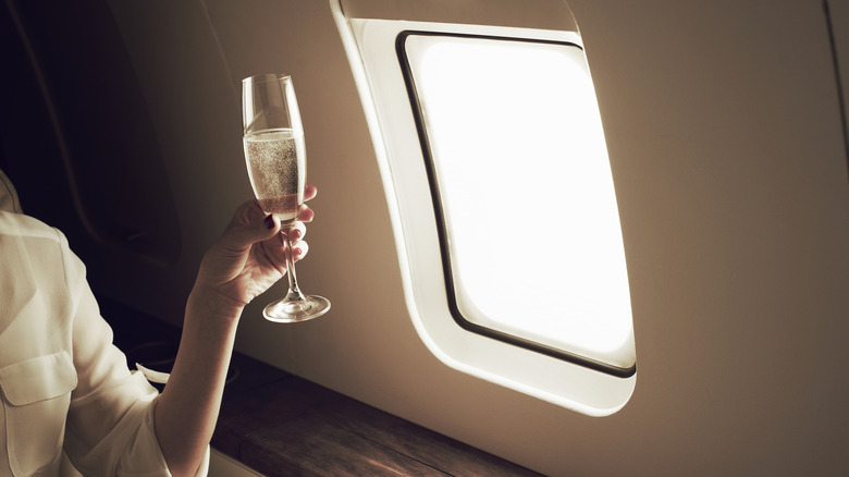 Woman drinking champagne in luxury airplane seat