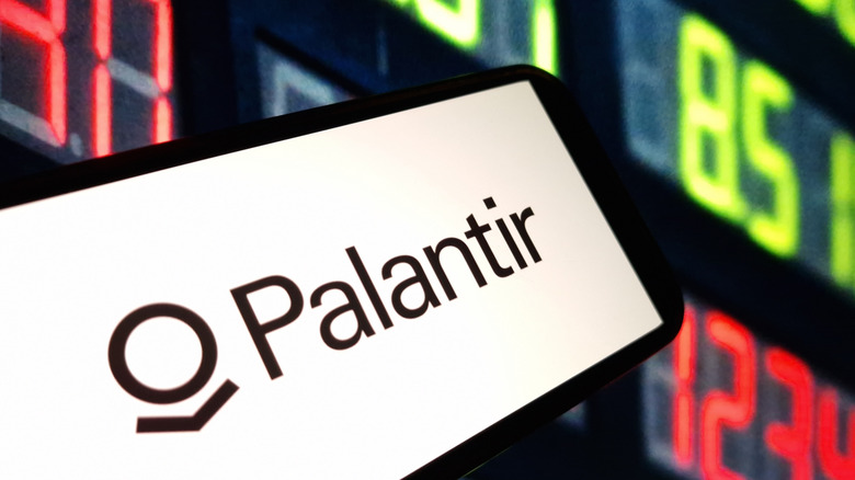 Palantir logo set against background of stock prices