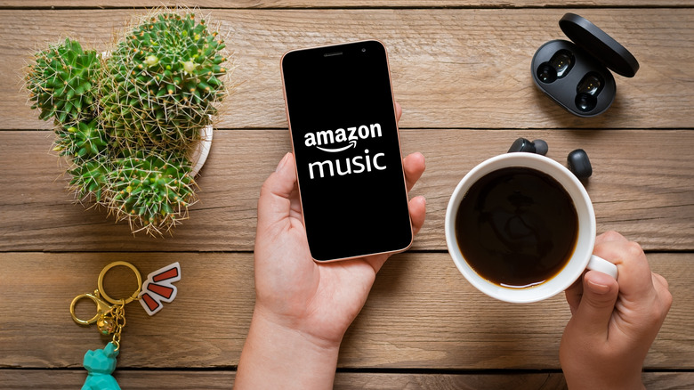 A hand holding a cellphone displaying Amazon Music