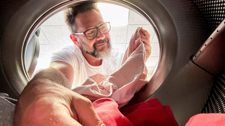 A middle aged man pulling laundry out a dryer