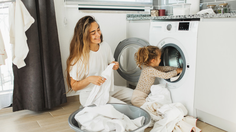 A woman doing laundry with a little girl