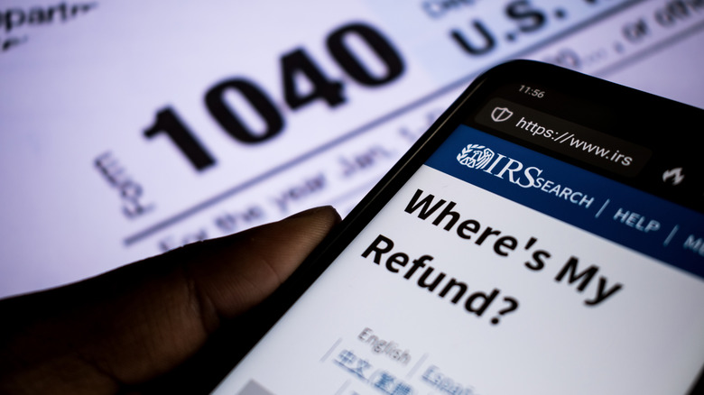 A cell phone screen showing "Where's My Refund?" with a tax form in the background.