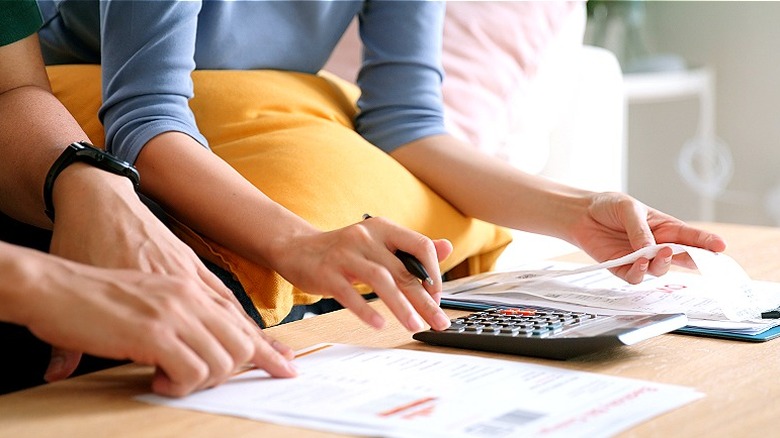 Couple sitting on couch, working on calculations at coffee table