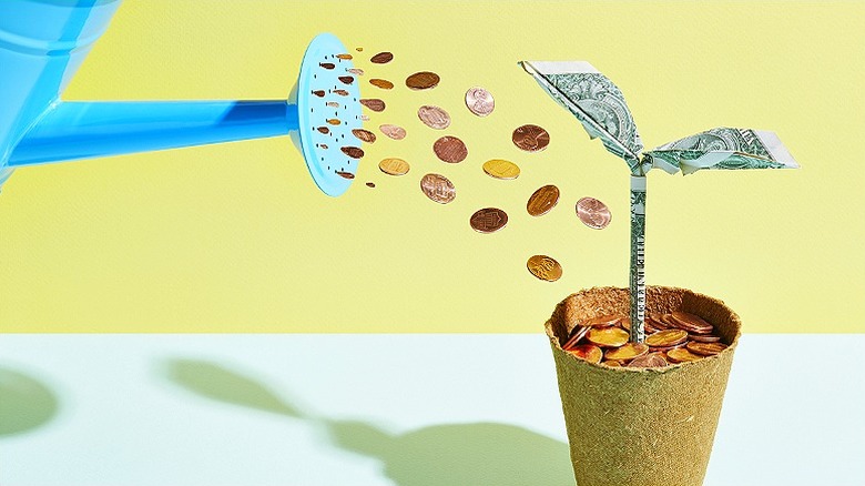 Coins falling from watering can into plant made out of origami money