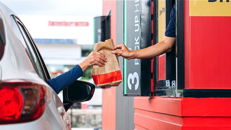 Person inside car receiving bag of food from fast-food window