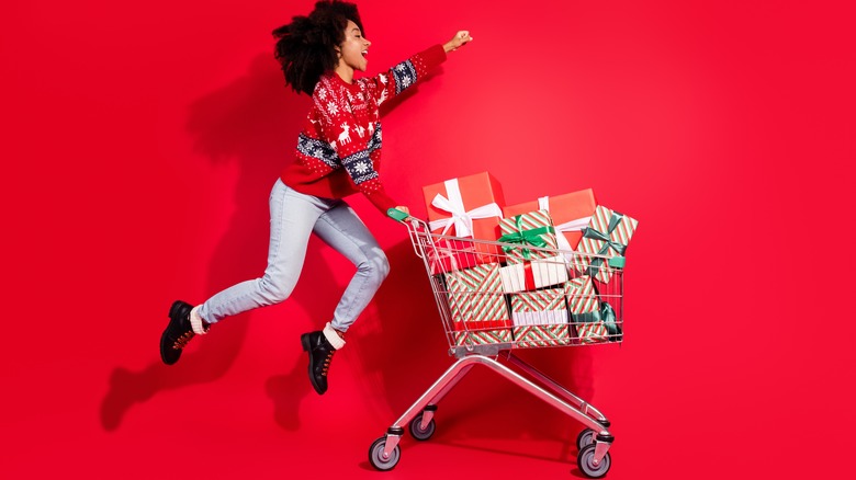 woman jumping with shopping cart full of gifts