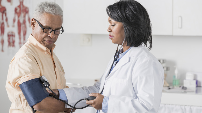 A doctor checking a senior man's blood pressure