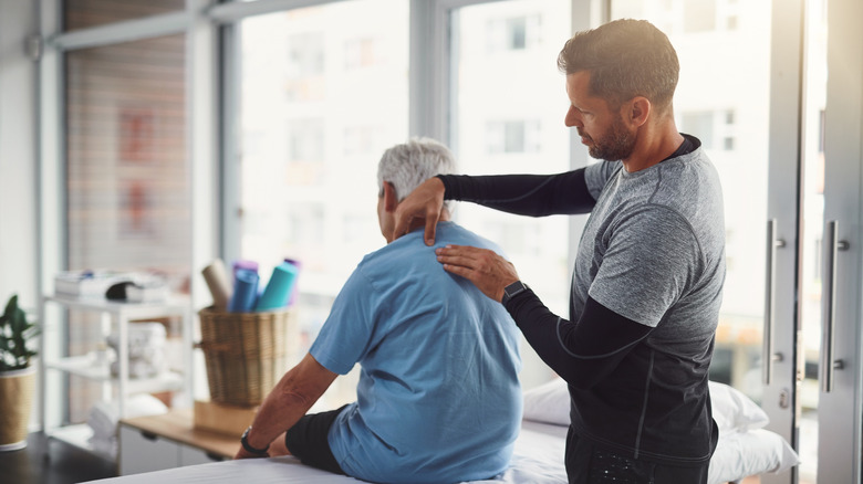 A massage therapist working on a senior man