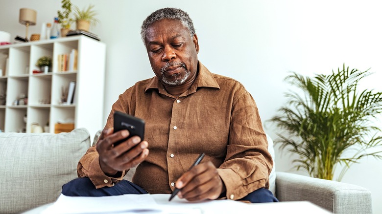 Older person reviewing paperwork with calculator in living room