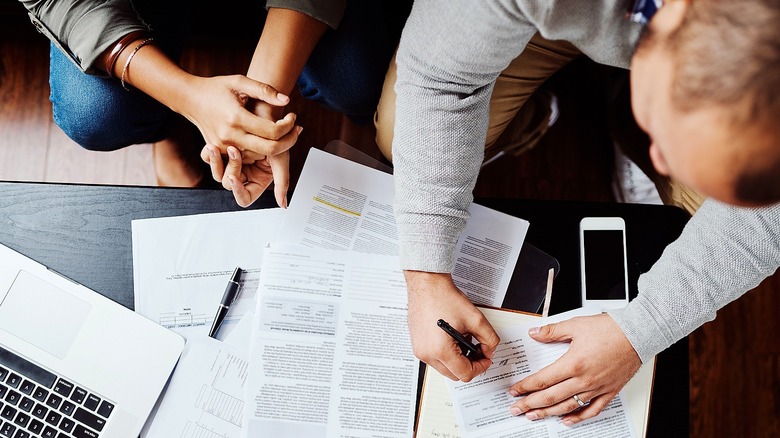 Above view of a couple signing documents together at a table