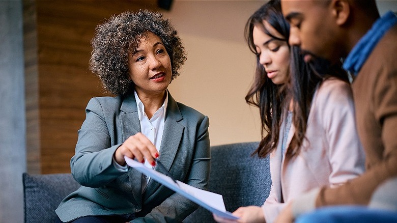 Adviser explaining a document's contents to a couple in an office