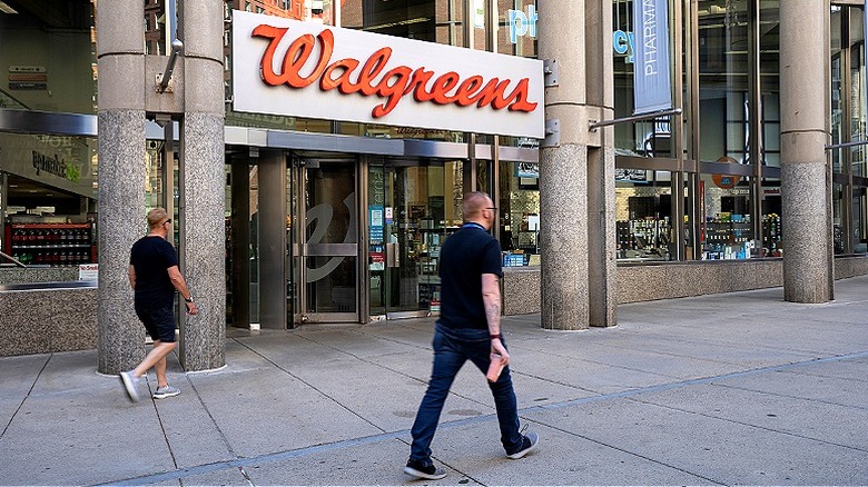 People walking on sidewalk past Walgreens entrance