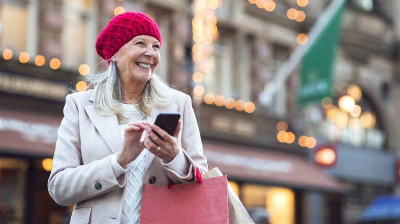 Person carrying bags, using smartphone