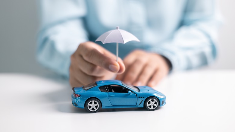 Person holding mini umbrella over model car