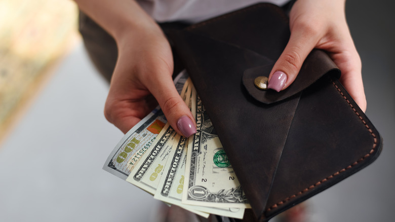 Woman holding cash in her wallet