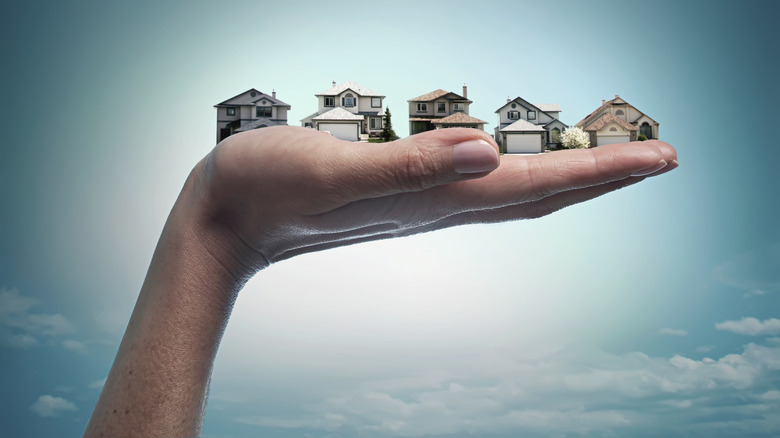 Miniature houses sitting in a person's hand