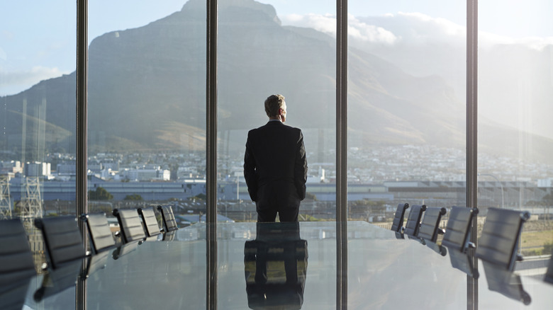 A businessman looking out a huge window with the skyline in view