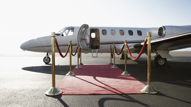 A red carpet leading to the open door of a small private jet.