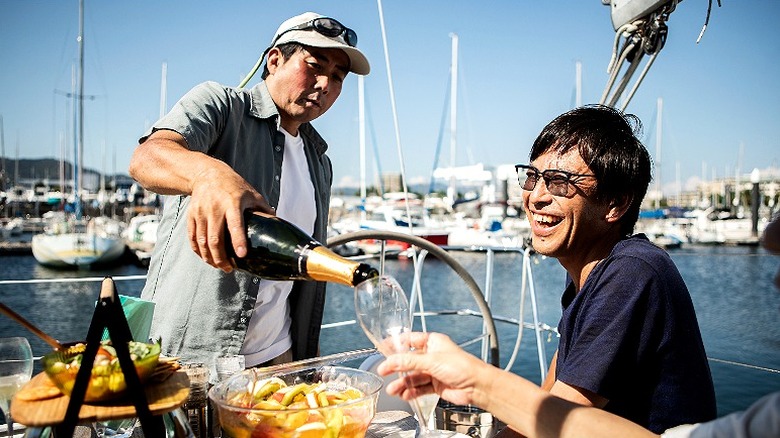 A man pouring champagne into a glass on a private yacht