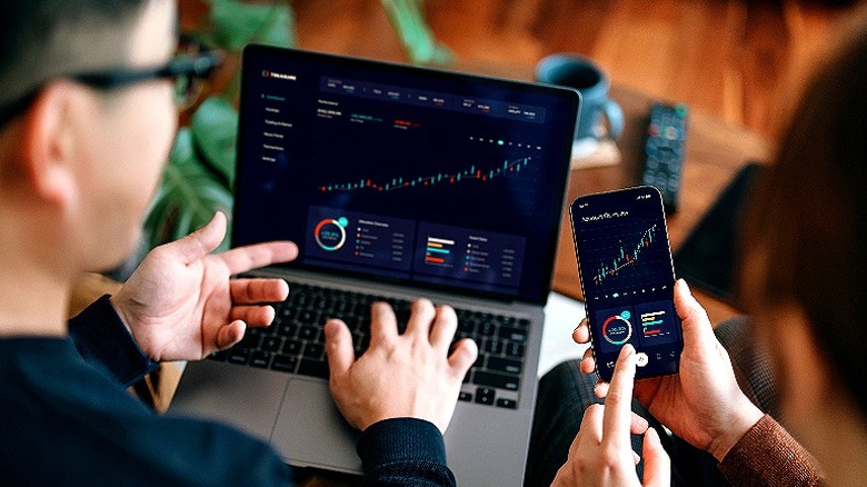 A couple investing online with a laptop and smartphone