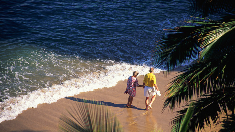 Elderly Couple walking on a tropical beach