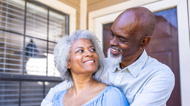 An elderly couple embracing and smiling at each other