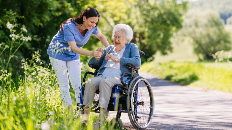 A young caregiver holding an elderly woman's hand