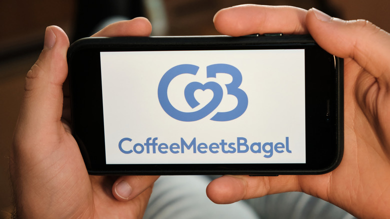 hands cupping a device with the logo of Coffee Meets Bagel om-screen